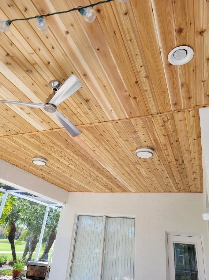 Portrait view of the cedar lanai ceiling around its white fan and lights